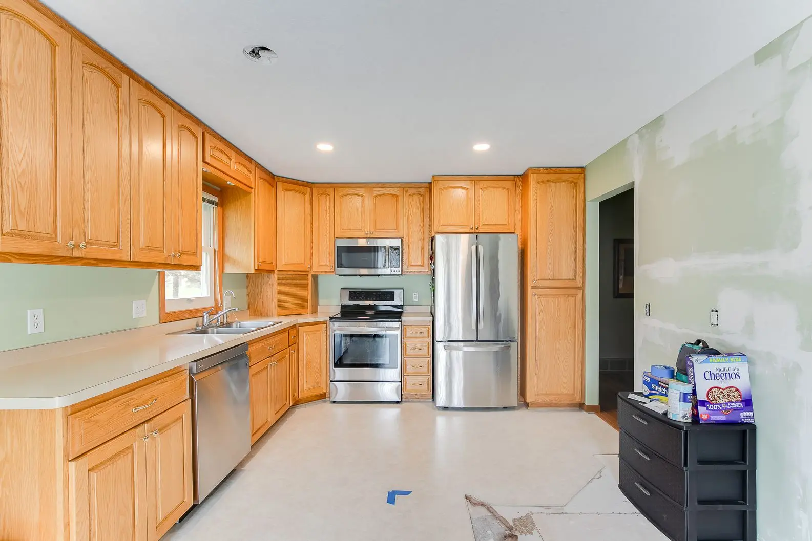 Kitchen renovation with corner sink, white tile backsplash, and wood cabinetry