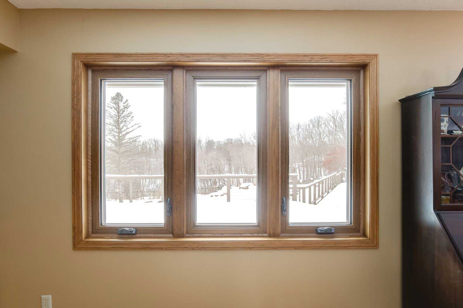 Set of brown-trimmed casement windows overlooking the yard