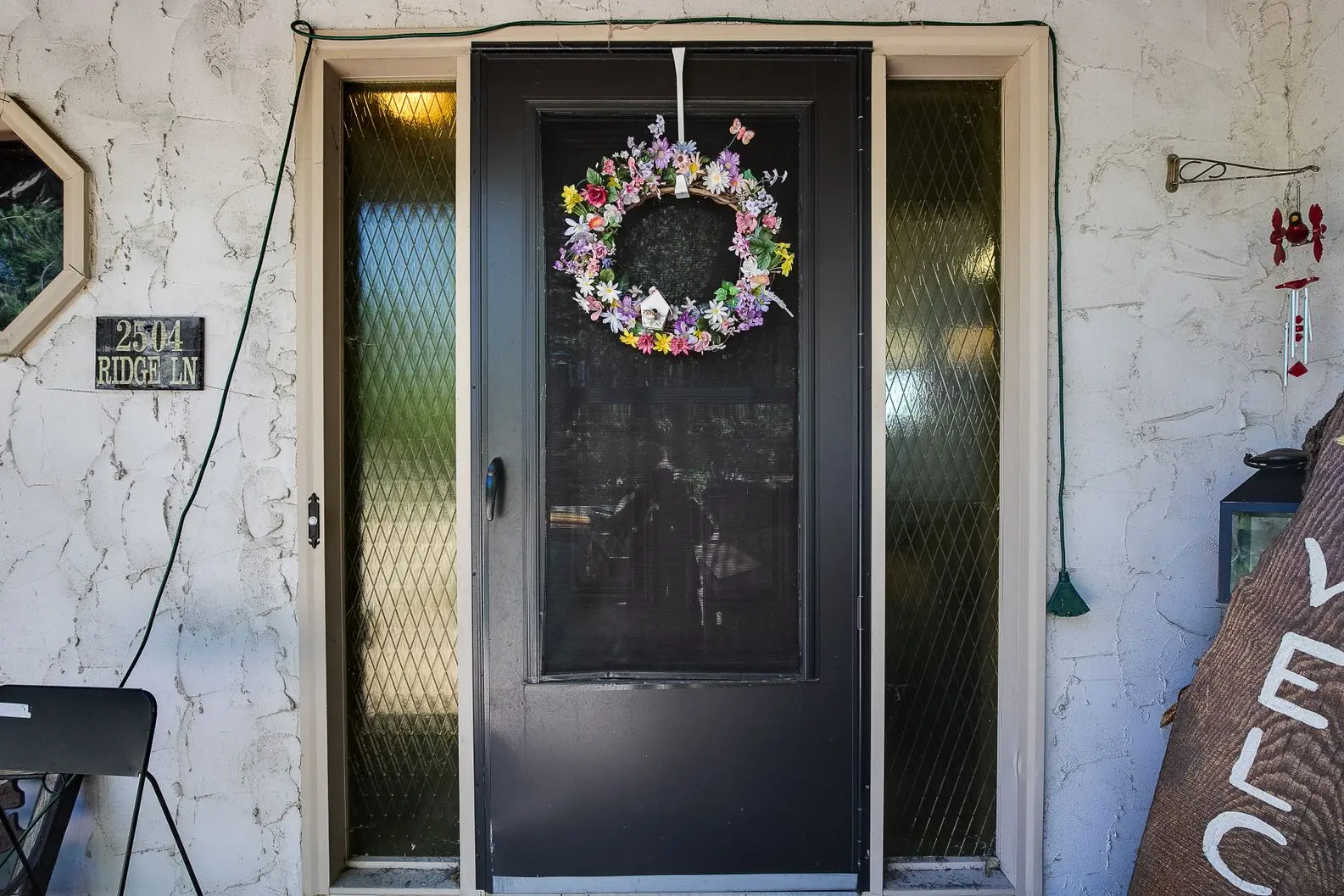 Black front door with glass panels and floral wreath entry design