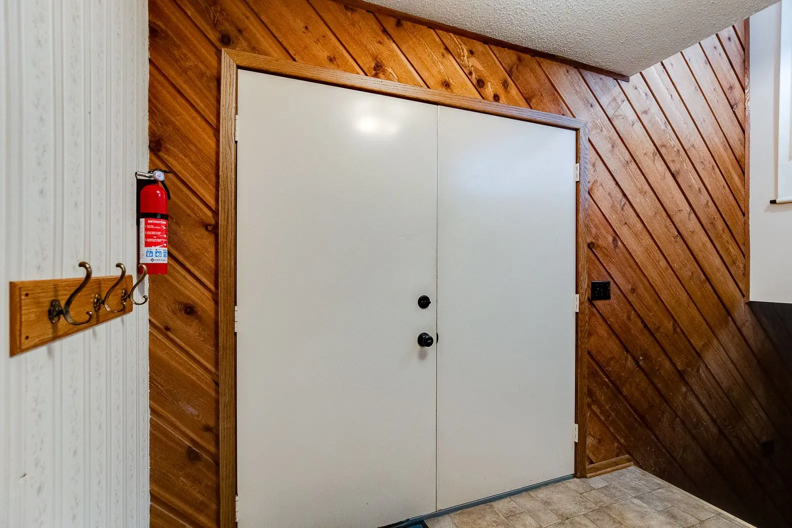 White double door replacement in wood-paneled entryway
