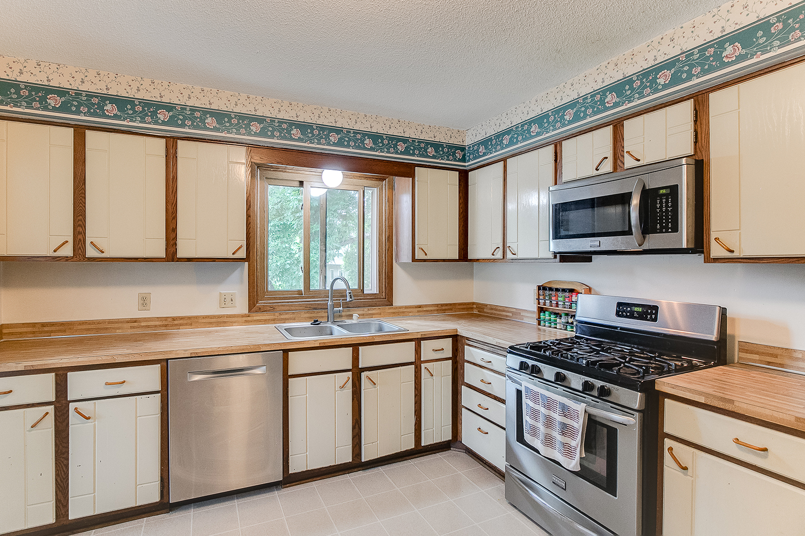 Updated kitchen with tile backsplash, wood cabinets, and new lighting