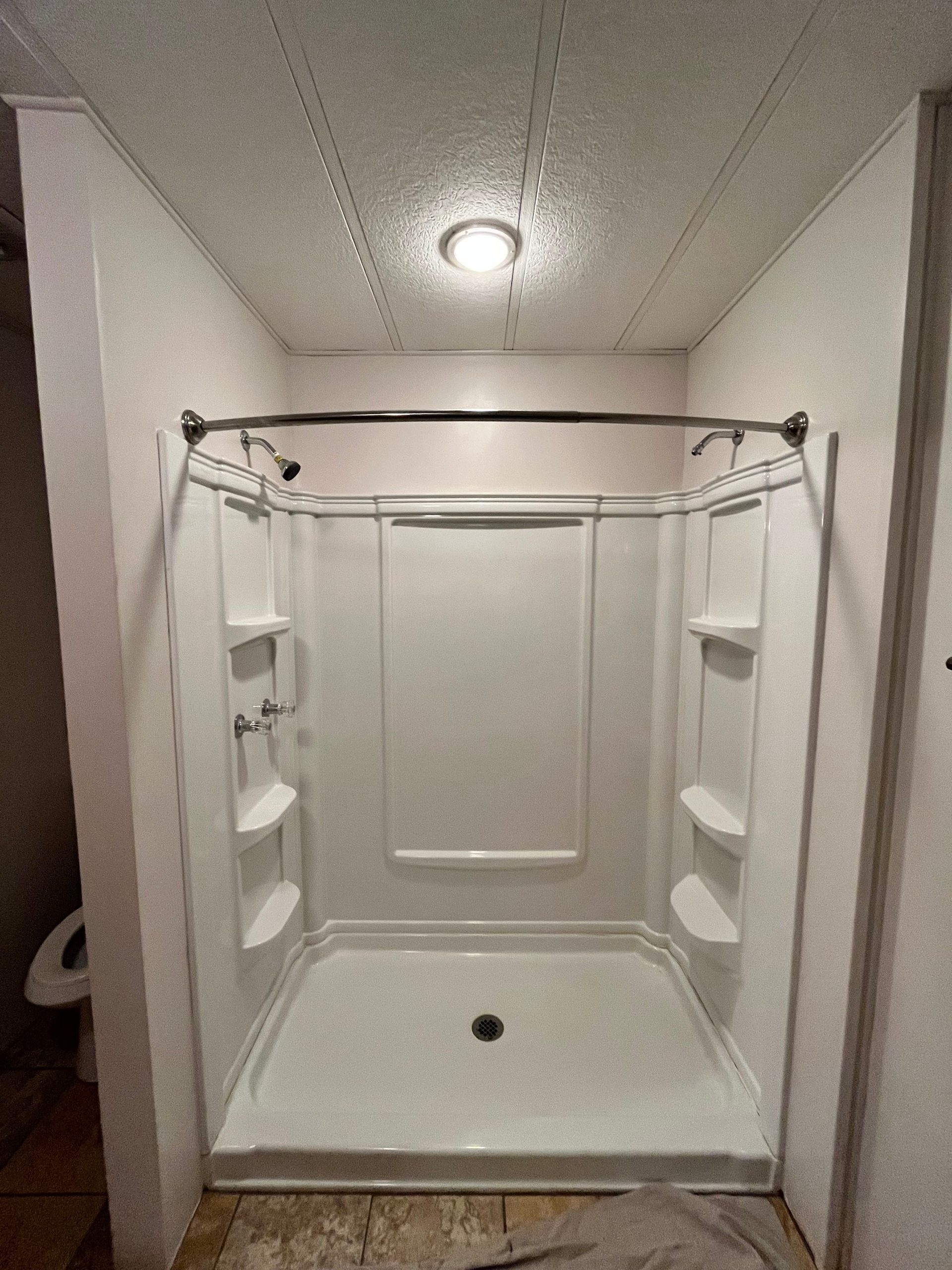 White walk-in shower with built-in shelving and updated fixtures