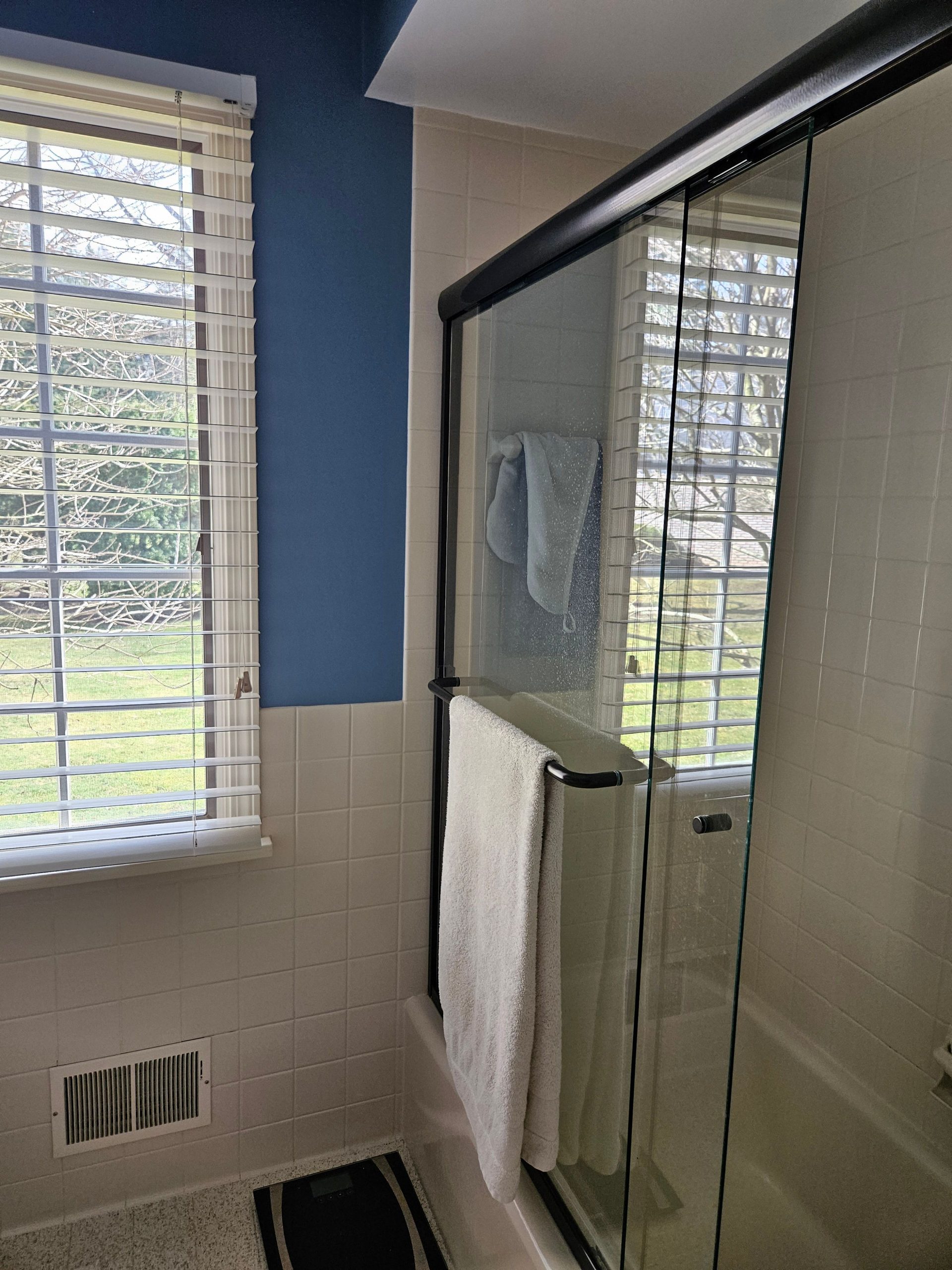 Modern walk-in shower with black fixtures and tile backsplash