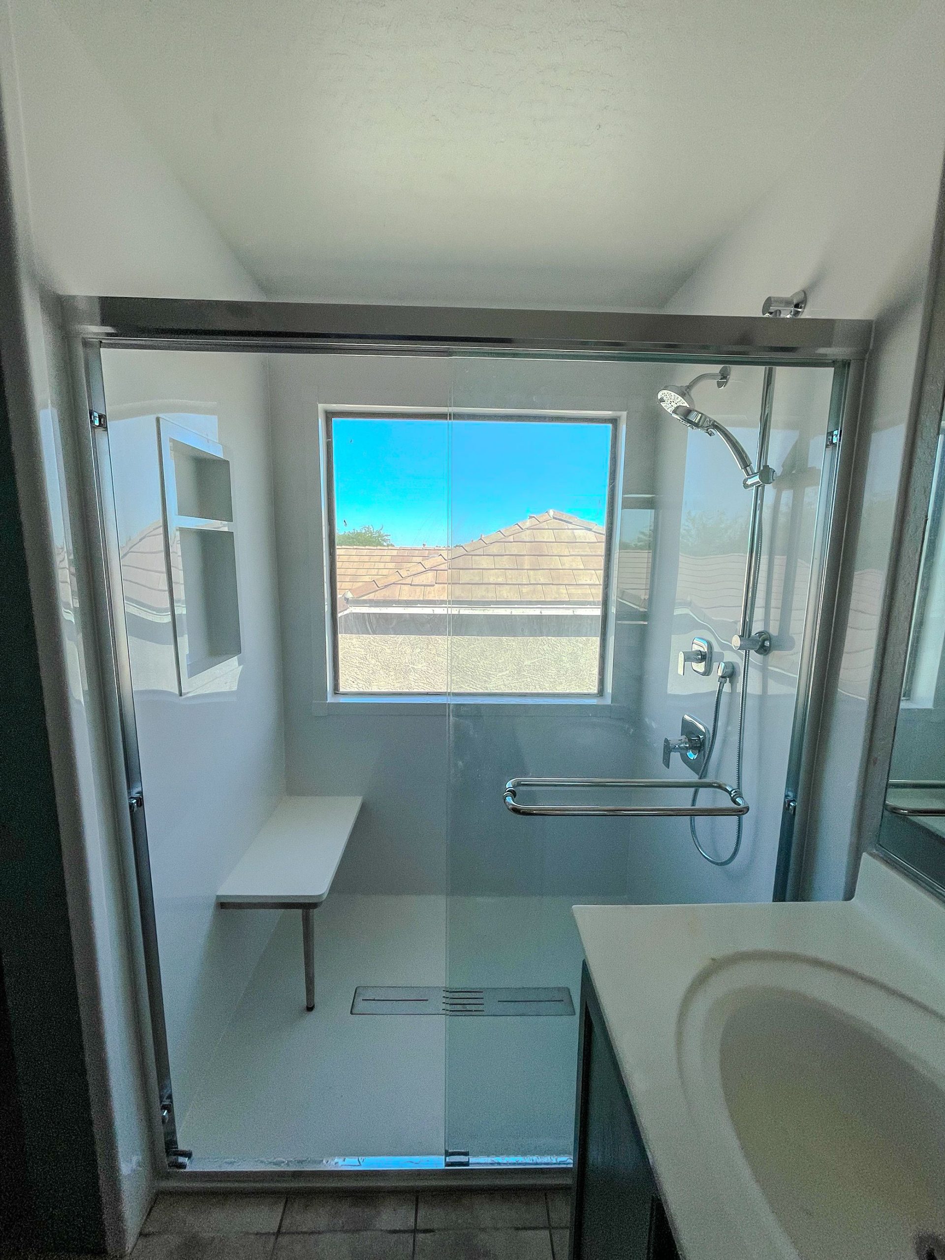 Gray tiled bathroom with new window installation above shower