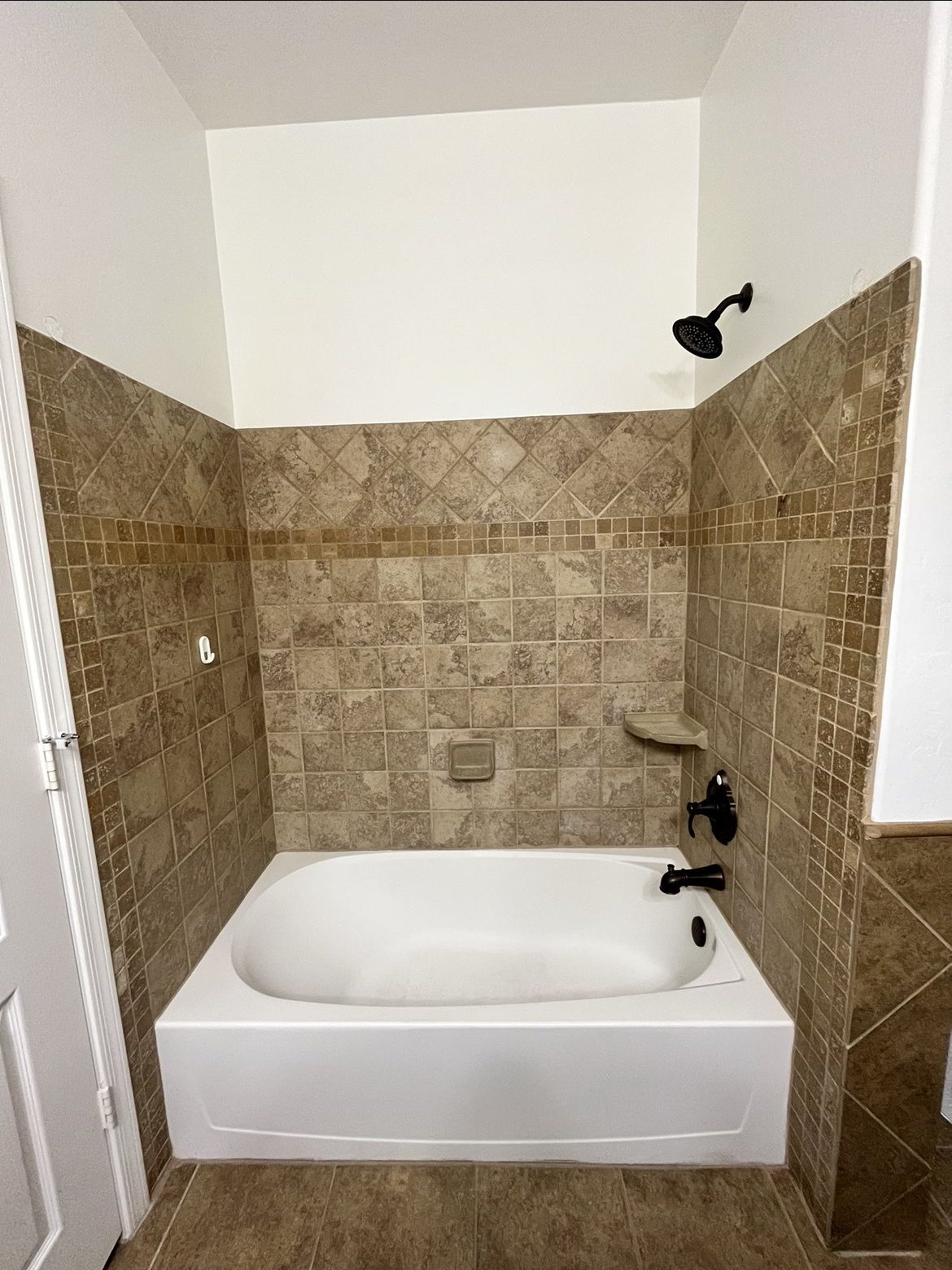 Bathroom remodel with tan tile walls and updated bathtub