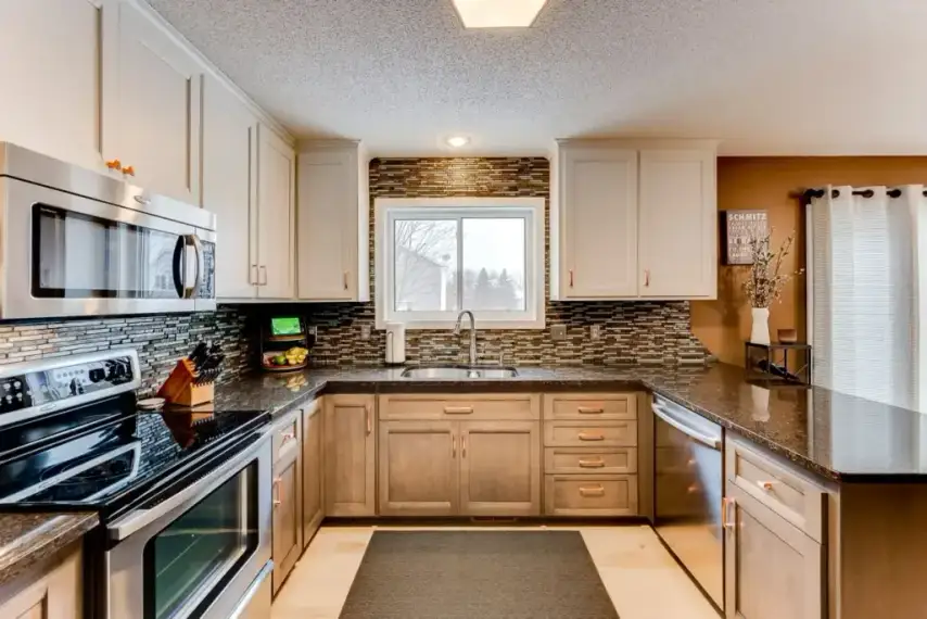 Modern kitchen with wood lower cabinets, white upper cabinets, and a horizontal tile backsplash.