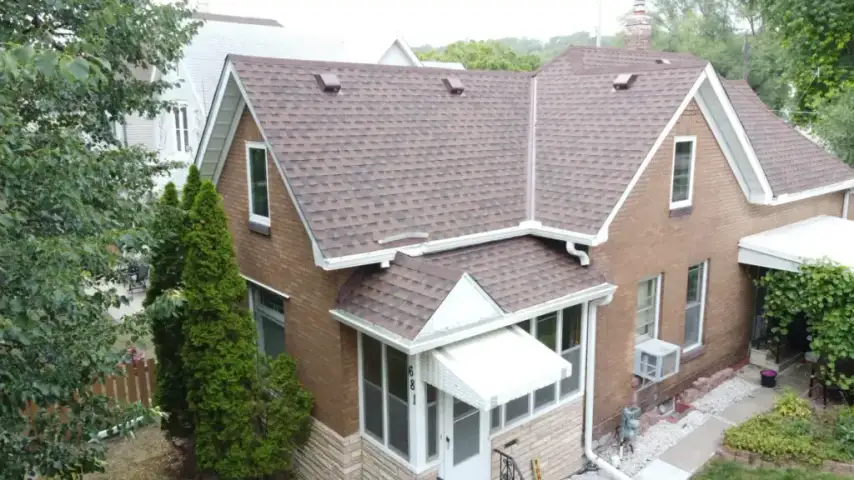Brown asphalt shingle roof on a multi-level brick house with white gutters and trim.