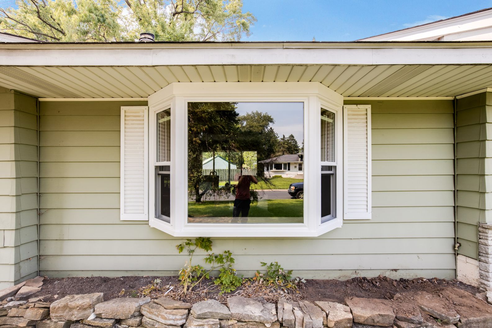Bay window replacement on single-story home with light green siding