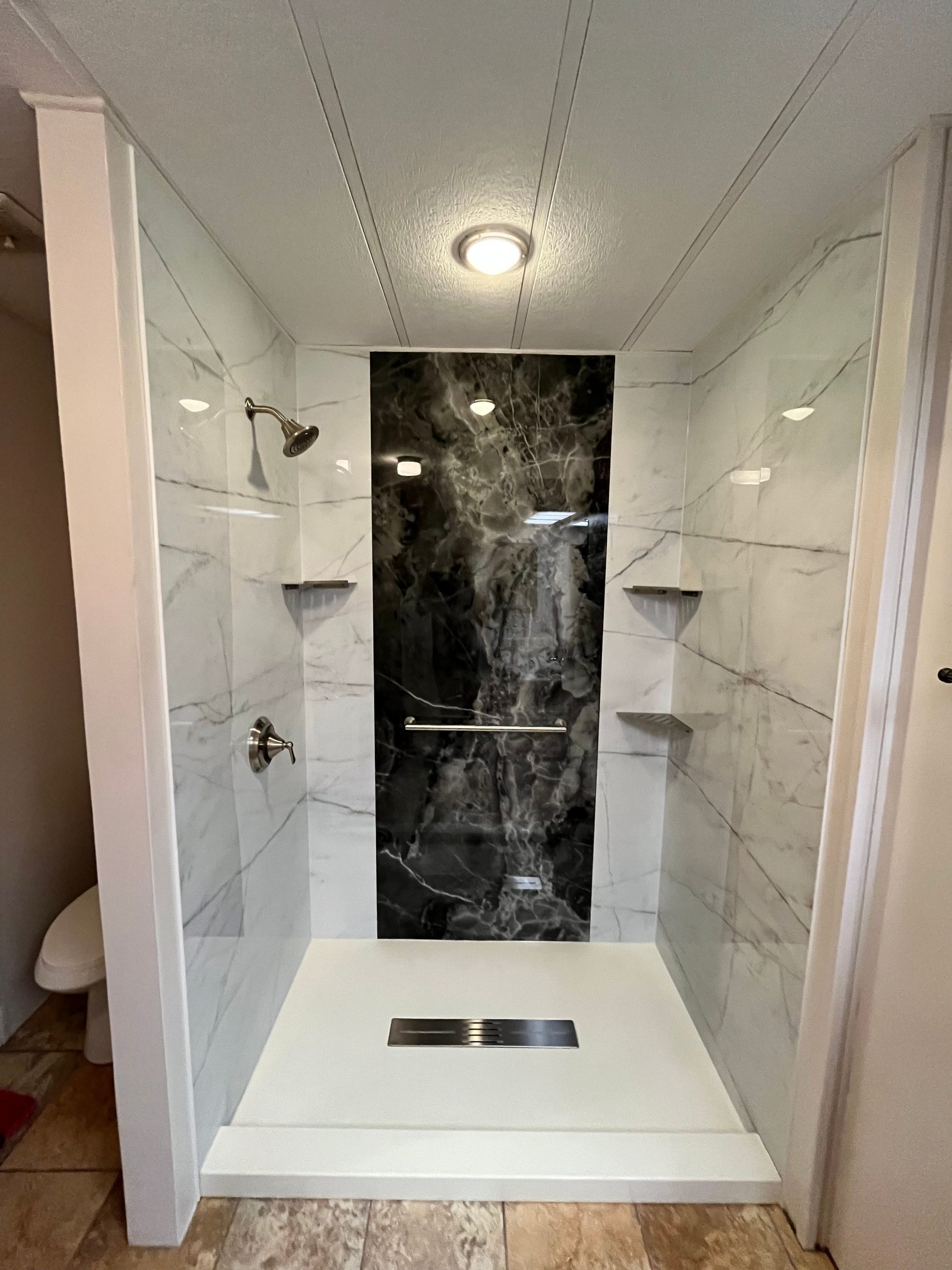 0269d28e79d711efb721cf54145333ee White walk-in shower with built-in shelving and updated fixtures