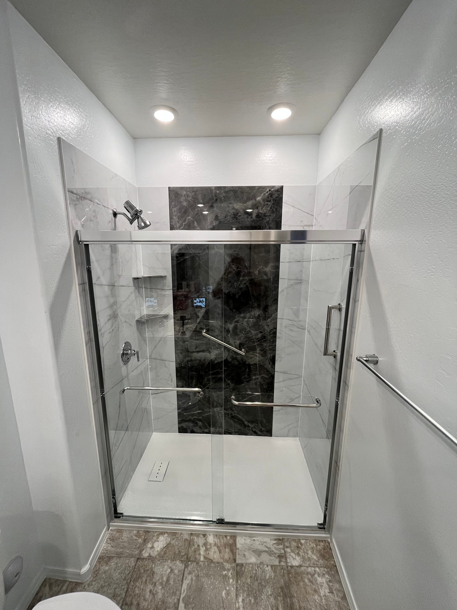 Updated bathroom with new tile, shower door, and wall fixtures