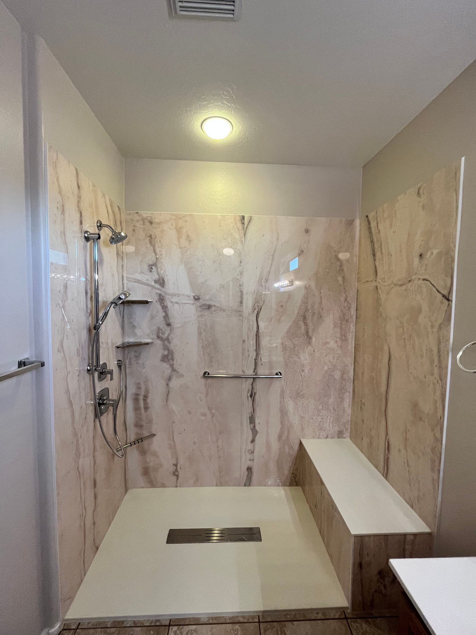 f10d5244210d11f0ac5cc9ca9afff916 White bathroom remodel with marble-style tile and built-in bench